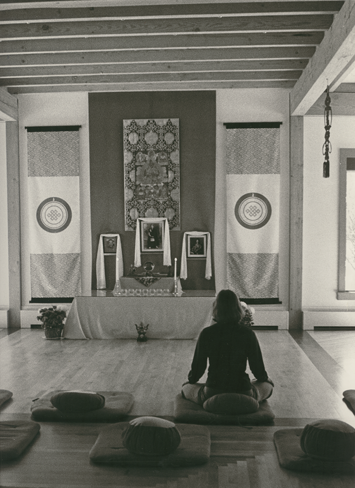 A woman sits on a meditation cushion at the newly-built shrine room at Karmê Chöling